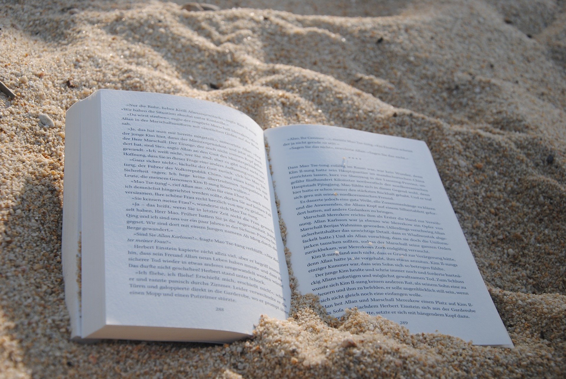 Un livre ouvert posé sur du sable